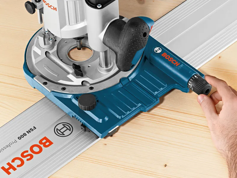 한 사람이 나무 표면 위에서 시스템 액세서리 트랙 가이드를 조정하고 있습니다.