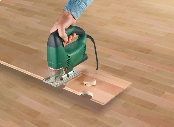 한 사람이 톱을 이용해 나무 판자에 원형 홈을 파고 있습니다.