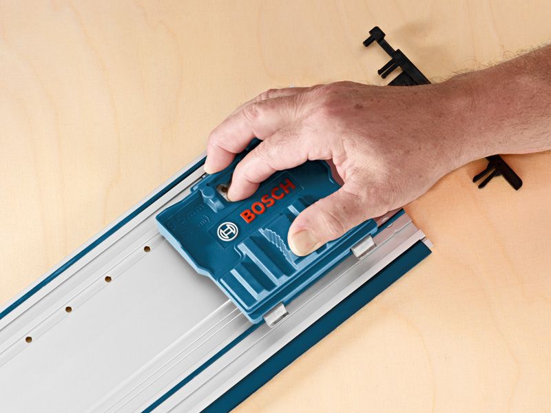 한 사람이 나무 표면에 놓인 금속 레일에 파란색 시스템 액세서리를 사용합니다.