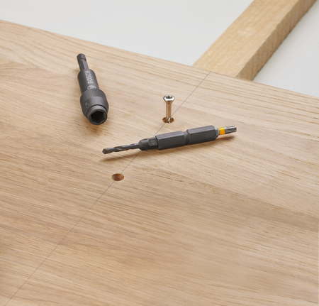 나사 옆 나무 판자 위에 드릴 비트와 드라이버 비트가 놓여 있습니다.