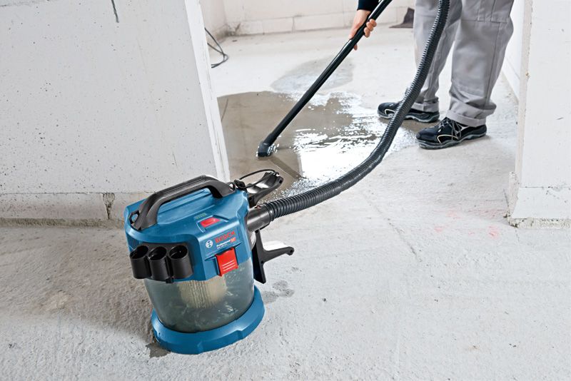 GAS 18V-10 L 한 사람이 무선 집진기를 사용해 콘크리트 바닥에서 액체를 청소하고 있습니다.