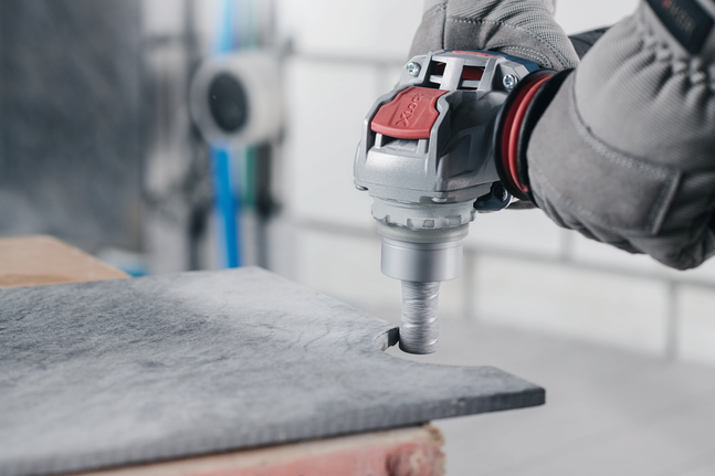 안전 장비를 착용한 사람이 돌판에 원형 구멍을 뚫고 있다.