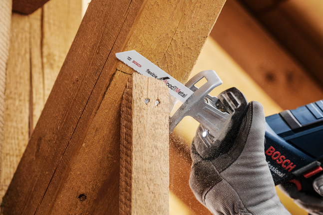 안전 장비를 착용한 사람이 왕복톱으로 나무 기둥을 자르고 있습니다.