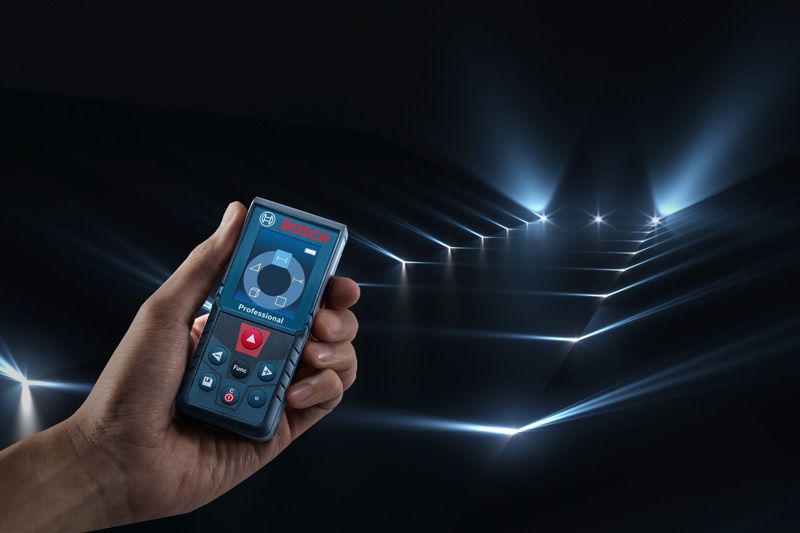 어두운 방에 여러 개의 측정 빔을 투사하는 레이저 측정기를 든 사람.