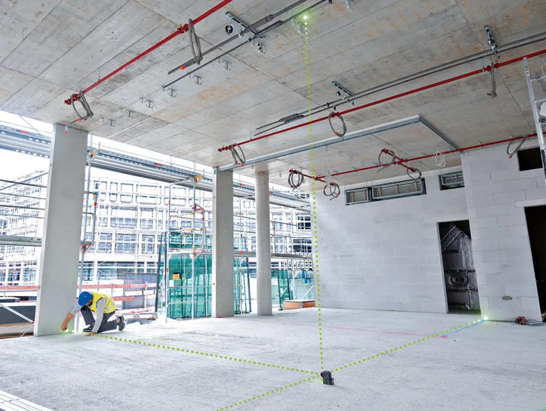 안전 장비를 착용한 사람이 레이저 레벨링 도구를 사용하여 공사 구역의 지점을 정렬합니다.