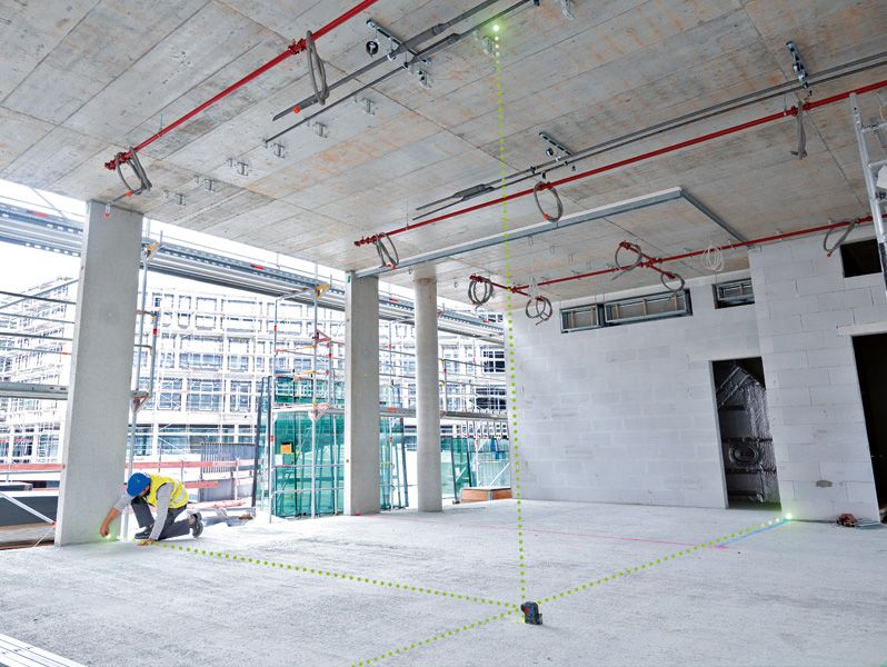 안전 장비를 착용한 사람이 레이저 레벨링 도구를 사용하여 공사 구역의 지점을 정렬합니다.