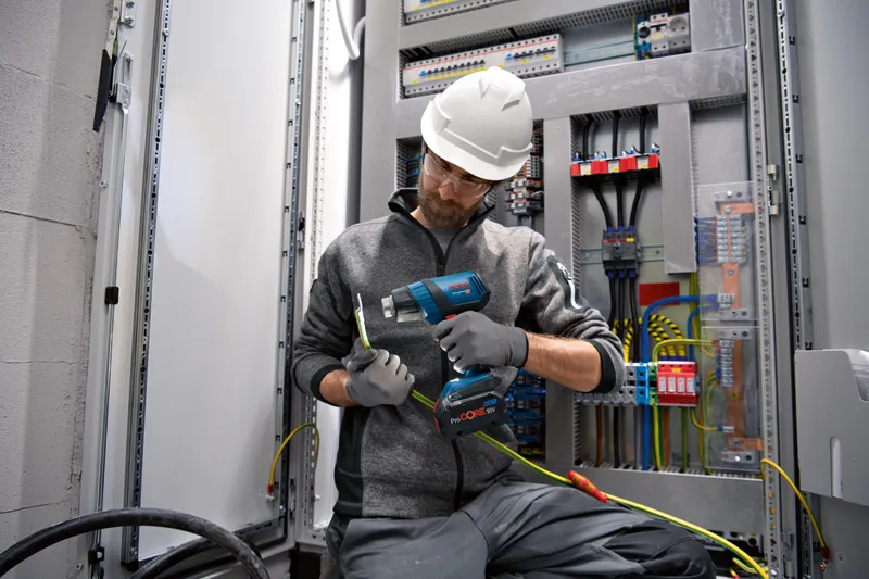 안전장비를 착용한 사람이 무선 열선총을 전기 배선에 사용하고 있습니다.