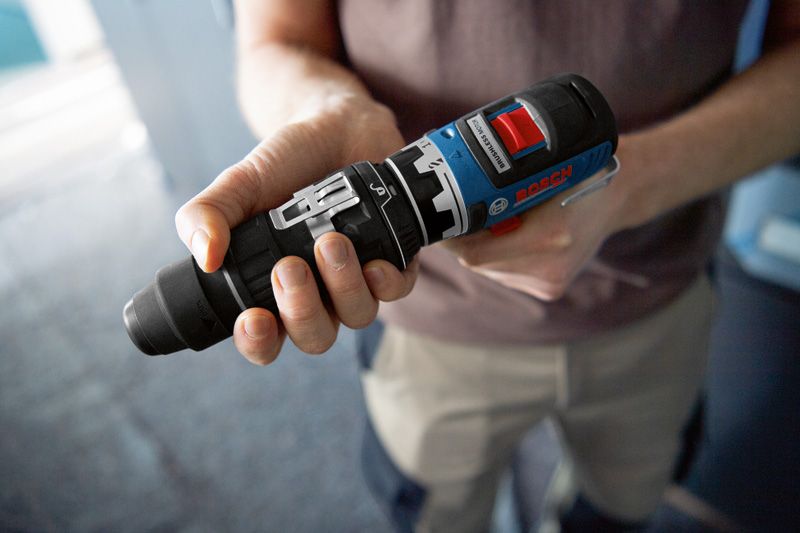 사람이 실내에서 전동 공구용 FlexiClick 어댑터를 잡고 있습니다.