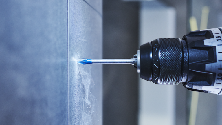 타일 벽에 구멍을 뚫는 전동 드릴.