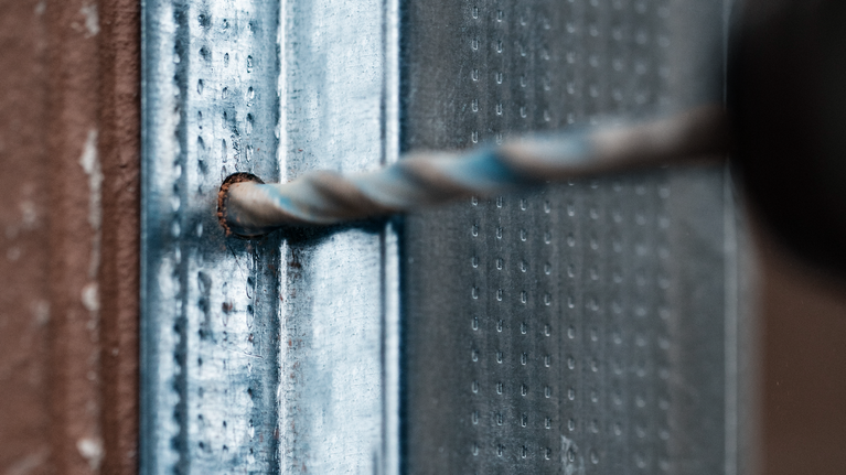 금속 표면에 구멍을 뚫는 드릴 비트.