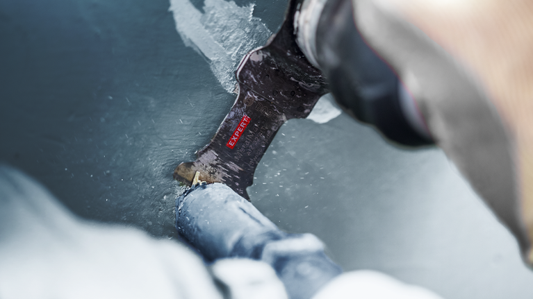 사람이 왕복 톱날을 이용해 페인트칠된 금속 파이프를 자르고 있습니다.