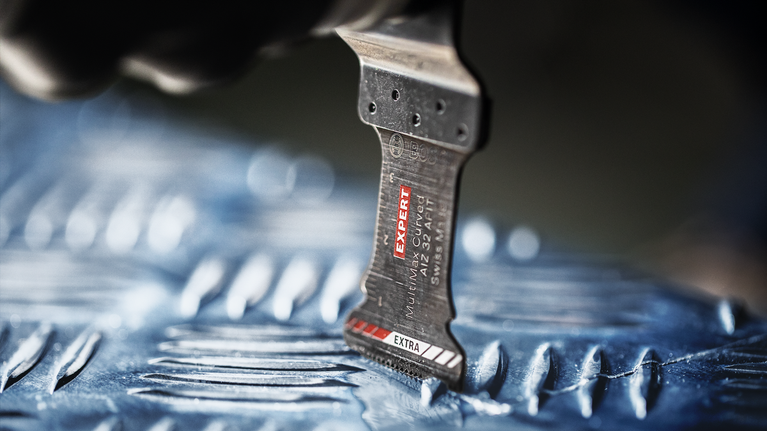 EXPERT MultiMax PAII 52 APIT 멀티툴 블레이드 52mm 톱날로 질감이 있는 금속 표면을 절단합니다.