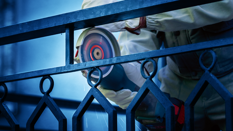 EXPERT Diamond Metal Wheel 대형 사이즈 컷팅 디스크 355 x 25.4mm 안전 장비를 착용한 사람이 전동 공구로 금속 울타리를 갈아내고 있습니다.