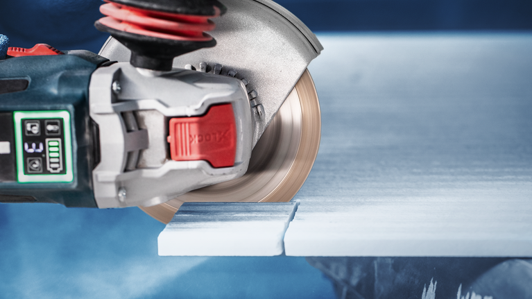 원형 톱으로 흰색 타일 슬라브를 절단하고 있습니다.