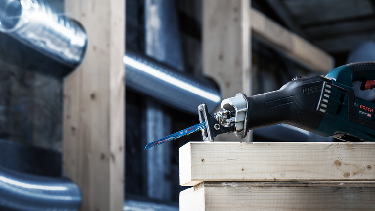 다양한 재질에 사용 가능한 날이 장착된 왕복톱으로 쌓아 놓은 나무 기둥을 절단하고 있습니다.