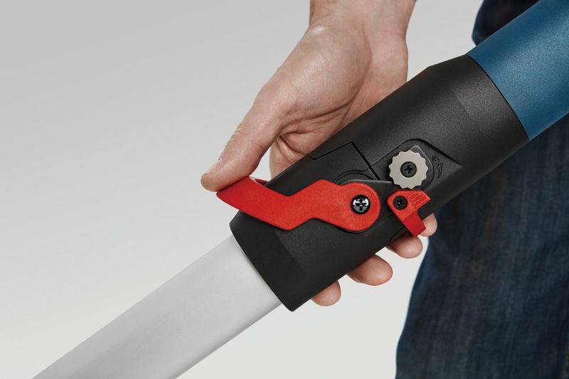 한 사람이 건식벽 샌더 손잡이의 빨간색 잠금 레버를 조정하고 있습니다.