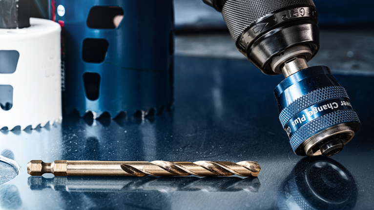 반사되는 금속 표면 위의 드릴 척과 드릴 비트를 클로즈업으로 찍은 사진입니다.