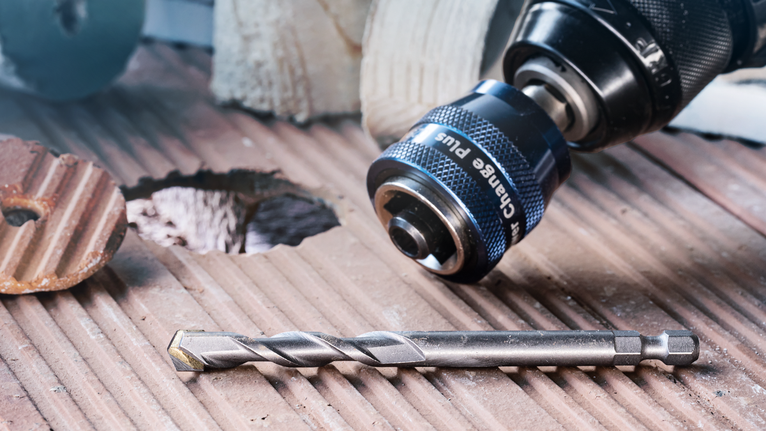 EXPERT Power Change Plus 파일럿 드릴 비트 HSS-G 7.15 x 105mm 새로 뚫은 구멍 옆의 홈이 있는 타일 표면에 드릴과 비트를 놓습니다.