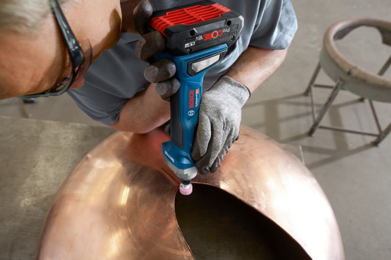 안전장비를 착용한 사람이 큰 금속 돔의 가장자리를 갈아내고 있습니다.