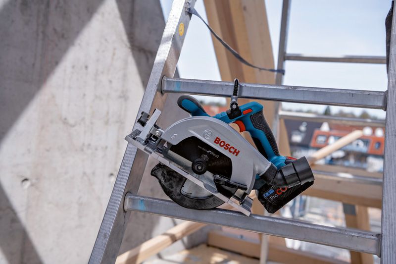 건설 현장의 금속 사다리 위에 놓인 무선 원형 톱.