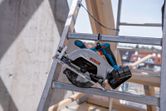 건설 현장의 금속 사다리 위에 놓인 무선 원형 톱.