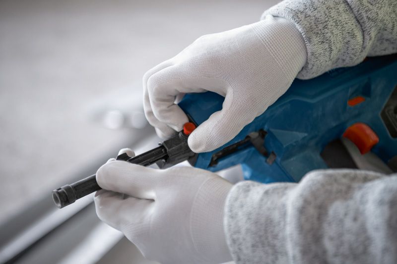 안전장비를 착용한 사람이 무선 콘크리트 못 박는 기계를 조정하고 있습니다.