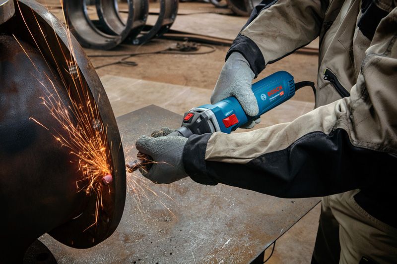 안전장비를 착용한 사람이 금속을 갈아서 밝은 불꽃을 일으킨다.