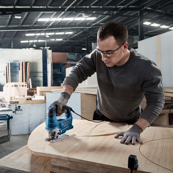 안전장비를 착용한 사람이 코어 드릴을 사용하여 콘크리트를 뚫고 있습니다.