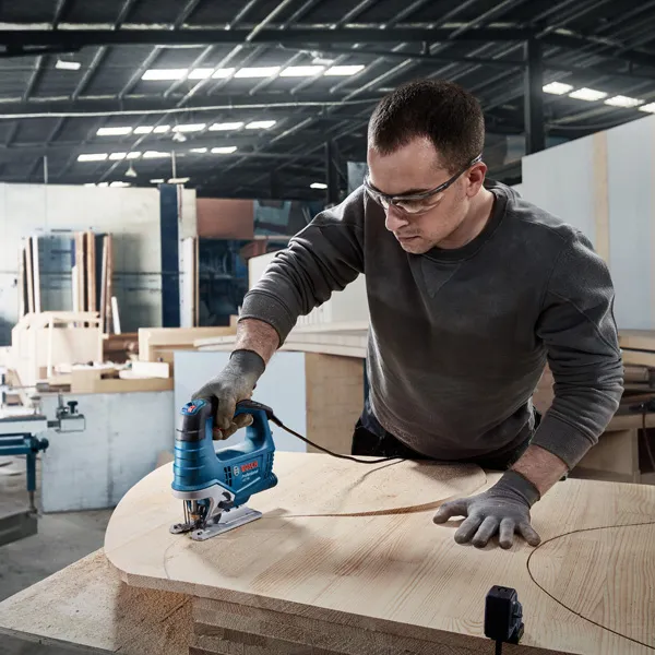 안전장비를 착용한 사람이 코어 드릴을 사용하여 콘크리트를 뚫고 있습니다.