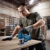 안전장비를 착용한 사람이 코어 드릴로 콘크리트를 뚫고 있습니다.