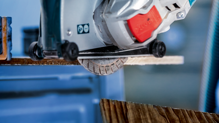 작업장에서 원형 톱으로 나무판을 자르고 있습니다.