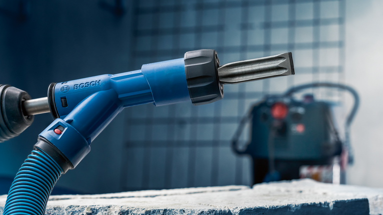 거친 콘크리트 블록 위에 끌이 부착된 회전 망치를 올려놓은 모습입니다.