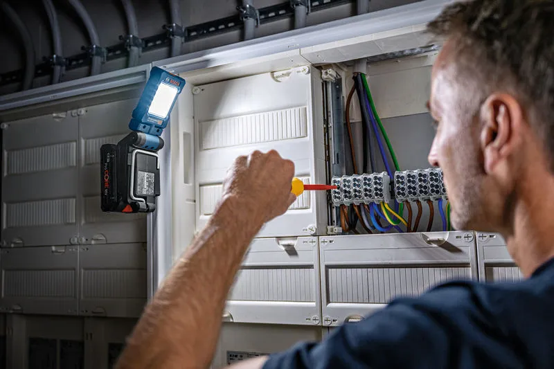 한 사람이 전기 패널에 드라이버를 사용하고, 조명을 위해 무선 전구를 부착했습니다.