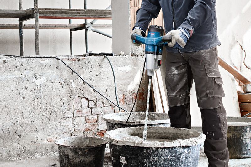 GRW 140 안전 장비를 착용한 사람이 교반 장치를 이용해 건축 자재를 섞고 있습니다.