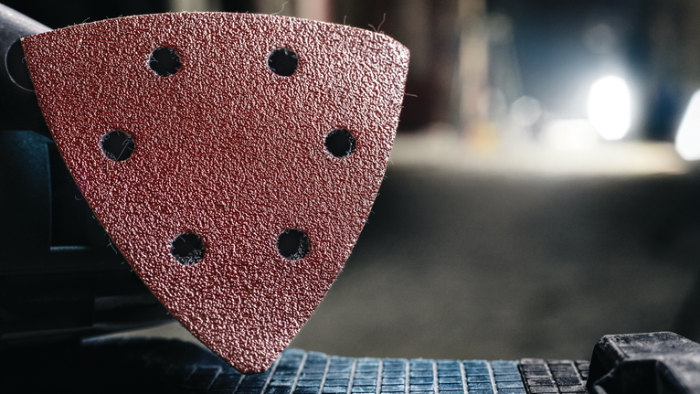 전동 공구에 부착된 삼각형 연마 패드의 세부 보기.