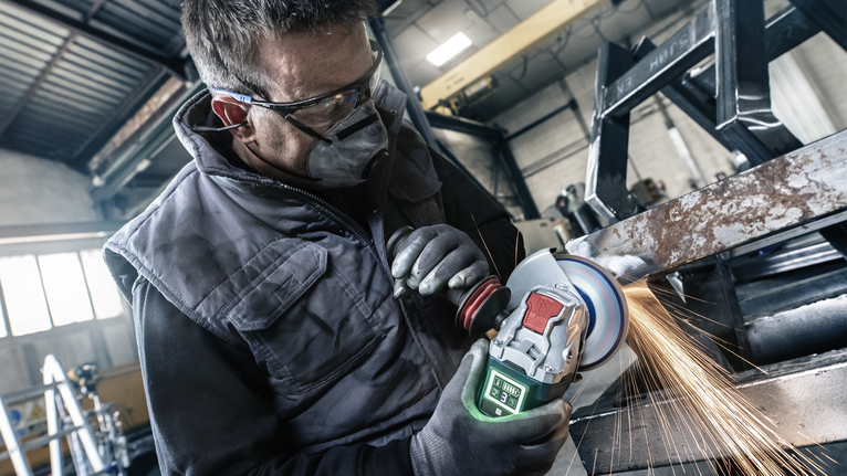 PRO X571 플랩 디스크, 직선, 125mm, G40, X-Lock 안전 장비를 착용한 사람이 금속 막대를 갈아서 밝은 불꽃을 낸다.