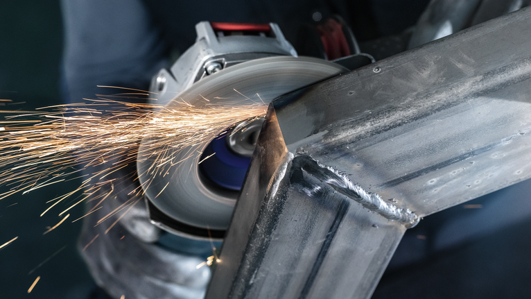 PRO X571 플랩 디스크, 직선, 125mm, G40, X-Lock 안전 장비를 착용한 사람이 금속을 갈아서 불꽃이 난다.