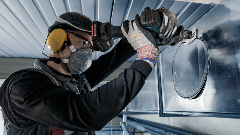 PRO Thin Metal S325GF 날, 1.25 x 7 x 85mm, 5개 안전 장비를 착용한 사람이 전동 공구를 사용해 금속 덕트에 원형 구멍을 뚫습니다.