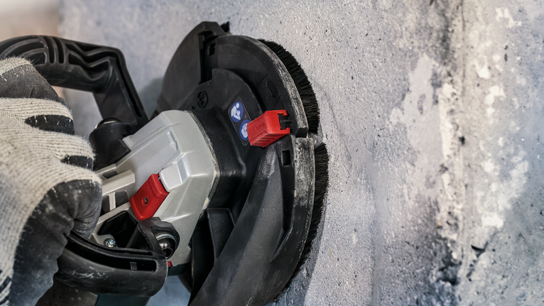 PRO Concrete 연마 헤드, 50 x 125mm, 22.23mm 안전 장비를 착용한 사람이 전동 공구를 사용하여 콘크리트 벽을 연마하고 있습니다.