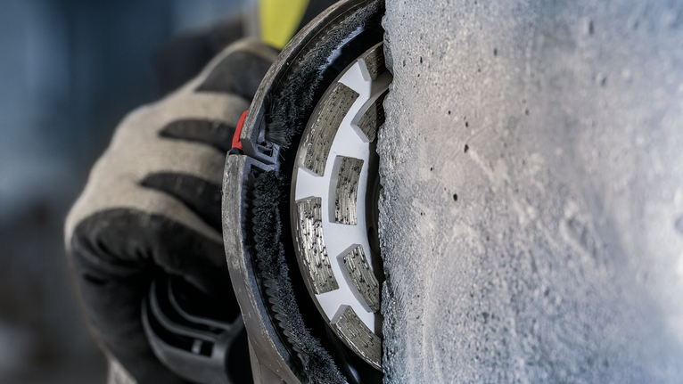 PRO Concrete 연마 헤드, 50 x 125mm, 22.23mm 안전장비를 착용한 사람이 다이아몬드 휠로 콘크리트를 갈아내고 있습니다.