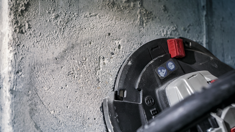 도구로 거친 콘크리트 벽을 갈아낸다.