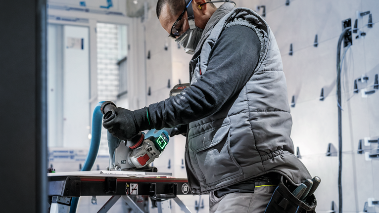 PRO Ceramic X-Lock 다이아몬드 디스크, 125 x 22.23mm, 22.23mm 안전 장비를 착용한 사람이 작업대에서 전동 공구를 사용하여 재료를 자르고 있습니다.