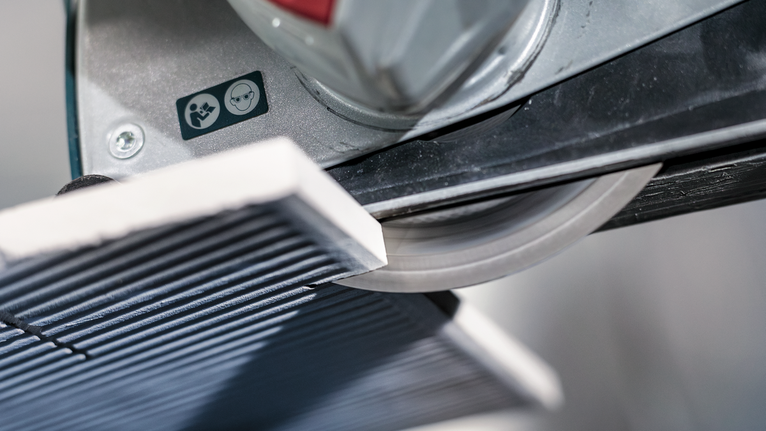 PRO Ceramic X-Lock 다이아몬드 디스크, 125 x 22.23mm, 22.23mm 작업장에서 타일 커터가 세라믹 타일을 자르고 있습니다.