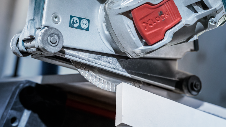 PRO Ceramic X-Lock 다이아몬드 디스크, 125 x 22.23mm, 22.23mm 안전 경고 라벨이 보이는 흰색 타일을 원형 톱으로 자르고 있습니다.