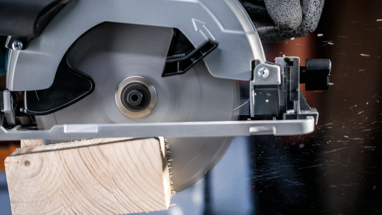 PRO Wood cordless 원형 톱날, 85 x 1.1 x 15mm 안전 장비를 착용한 사람이 원형 톱으로 나무 판자를 자릅니다.