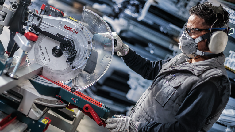 PRO Aluminium cordless 원형 톱날, 254 x 2.4 x 30mm 안전 장비를 착용한 사람이 작업장에서 원형 톱을 조정하고 있습니다.