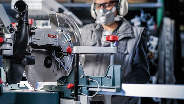 PRO Aluminium cordless 원형 톱날, 254 x 2.4 x 30mm 안전 장비를 착용한 사람이 작업장에서 원형 톱을 조작하고 있습니다.