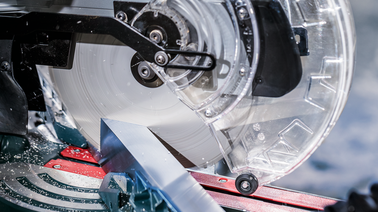 작업장에서 금속 톱이 알루미늄 조각을 자르고 있습니다.