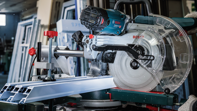 작업장에서 마이터 톱으로 알루미늄 프로파일을 절단하는 모습입니다.