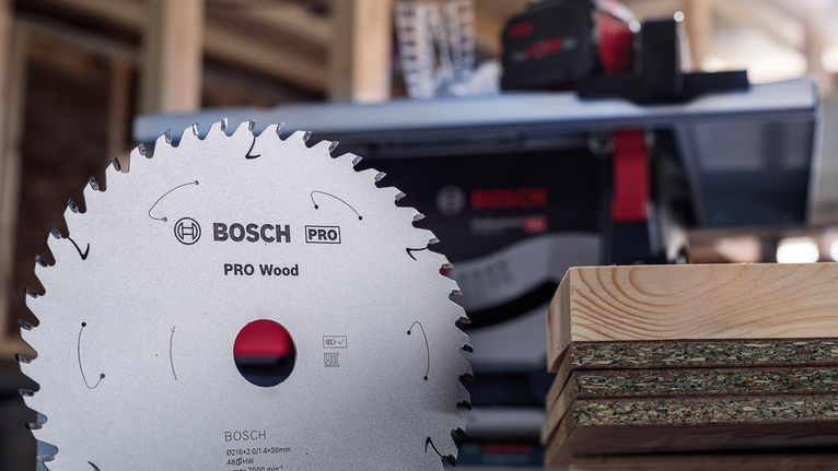 작업장에 쌓여 있는 나무 판자 앞에 놓인 원형 톱날.